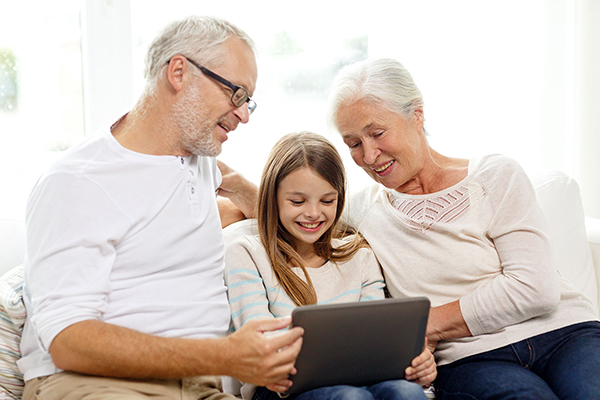 two grandparents looking at a tablet with their grand daughter