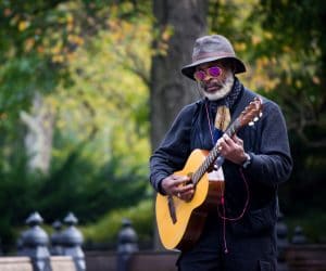 Elderly man playing a guitar in a park
