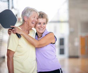 two senior woman embracing pickelball