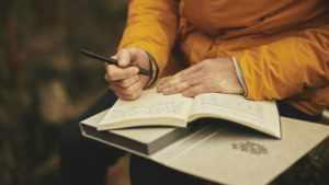person in yellow coat writing in a journal