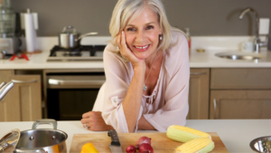 happy older adult woman in kitchen preparing food