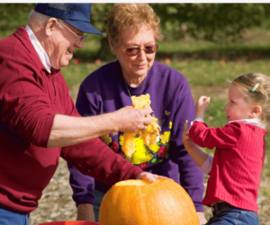 grandparents carving pumpkin with grandchild